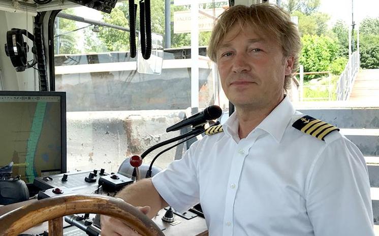 Kapitän mit weißem Kurzhemd am Steuerrad