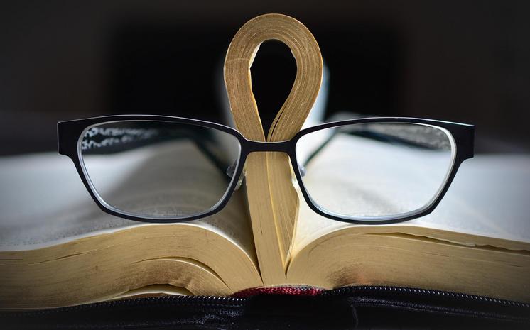 Aufgeschlagenes Buch und Brille. Symbolbild.